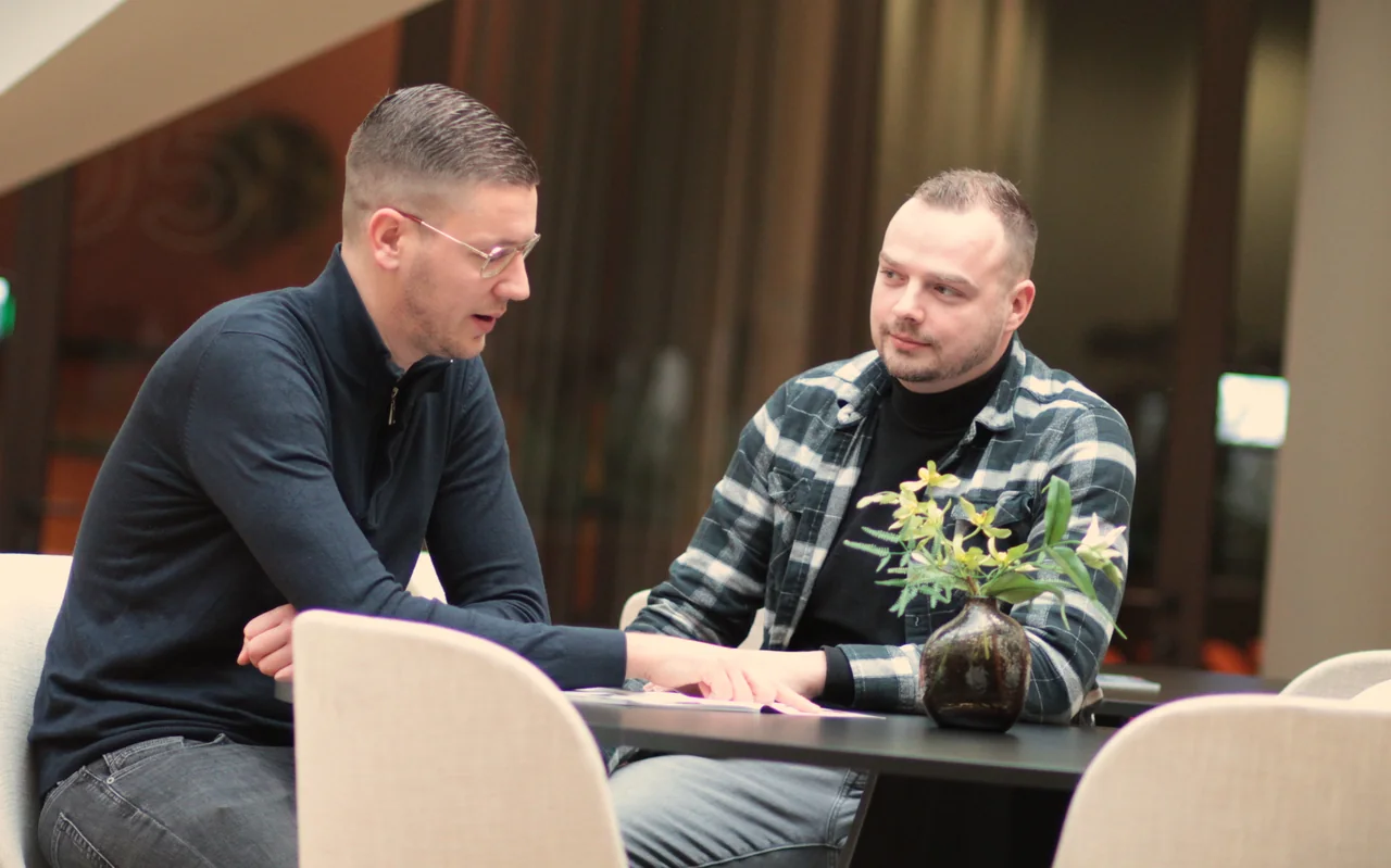 Twee mensen in gesprek aan tafel, met documenten